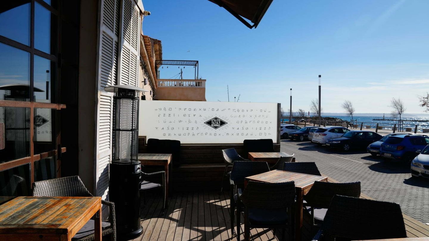 Terraza de madera con vistas al mar y el emblema de Izizi Nunnak pintado en el muro blanco.